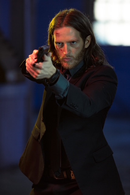 Russell Snipes. Action still aiming a handgun in a dim interior