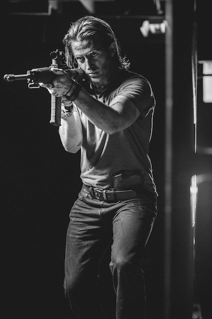 Russell Snipes. Black-and-white action still aiming a rifle