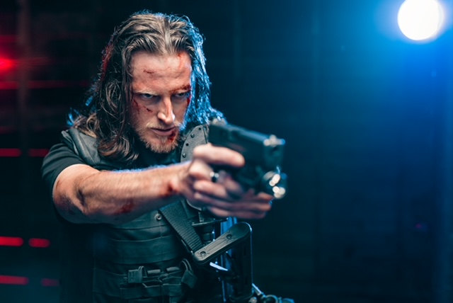 Russell Snipes. Tactical action still aiming a handgun under blue light