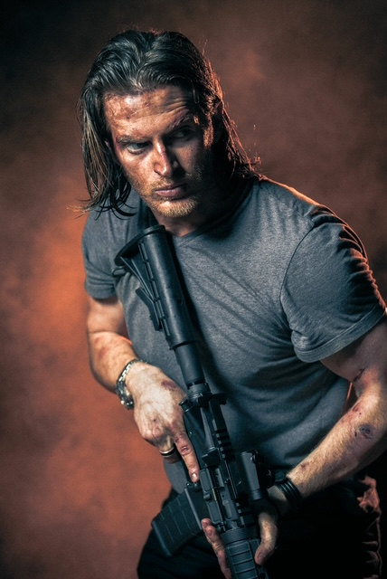 Russell Snipes. Holding a rifle in a dark tactical shirt