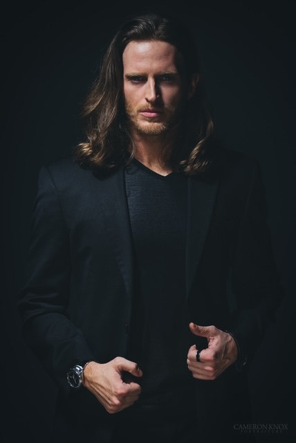 Russell Snipes. Portrait in a dark jacket against a dark backdrop