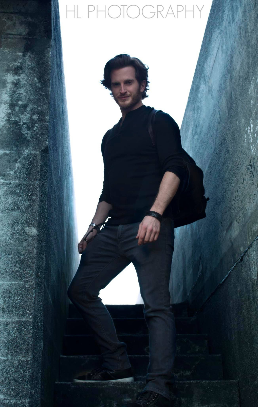 Russell Snipes. Full-length all-black outfit in a concrete corridor